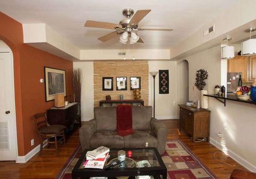 Tan living room with a couch, table, chair with a view of the kitchen from black breakfast bar